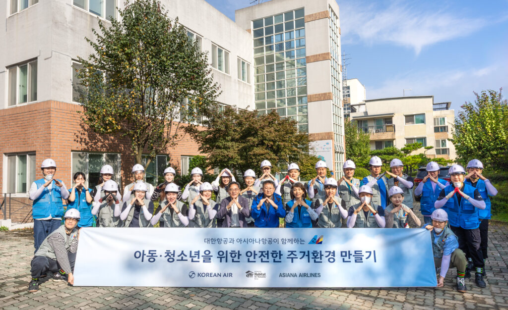 봉사활동에 참여한 대한항공-아시아나항공 양사 임직원 20여 명이 노후화된 벽지 교체 등을 지원하고 기념사진을 촬영하는 모습