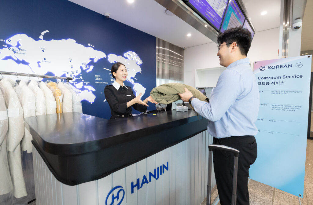 코트룸 접수 한진택배 카운터에서 승객이 직원에게 외투를 건네고 있다.